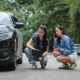 two women examining damaged vehicle after a car accident - Is it illegal to settle a car accident privately
