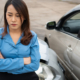 Woman with crossed arms standing next to car accident scene - can you reopen a settled car accident case?