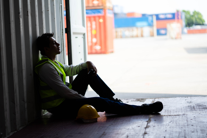 Anguished factory worker sitting next to a cargo container - is emotional distress a personal injury