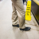 Person standing next to a caution wet floor sign at a grocery store - are slip and fall cases in Georgia hard to win?