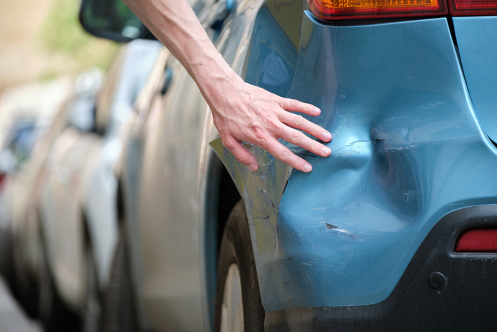 Person touching and inspecting vehicle damage after a hit and run - Who pays for a hit and run?